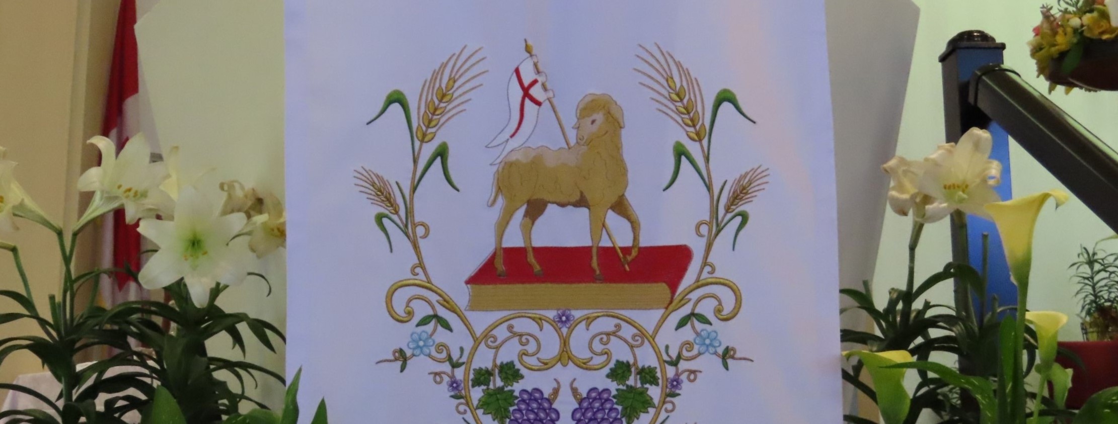 A picture of an ambo with an Easter banner with a lamb on it, surrounded by lillies